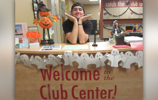 Person posing at the welcome to the Club Center! desk