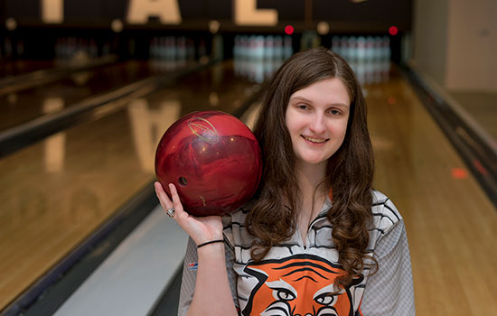 Laura Branch holding a bowling ball in front of bowling lanes