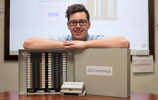 Brandon Hudson standing behind his thermostat system.