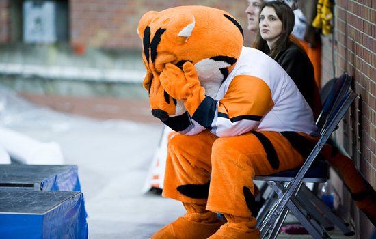 Tiger mascot sitting in a fold chair with his hands covering his eyes.