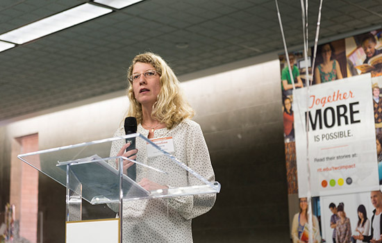 Blonde woman speaking at podium.