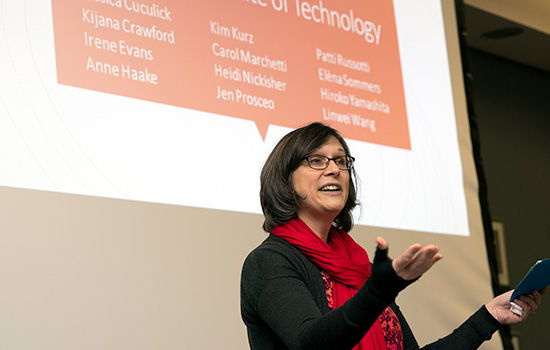 Person with red scarf presenting in front of screen.