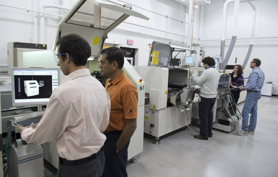Students and researchers work at large equipment in the CEMA lab.
