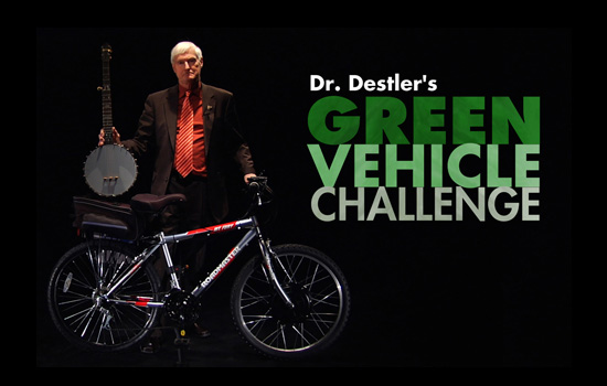 graphic of President Destler holding a banjo and bike with the text: Dr. Destler's Green Vehicle Challenge.