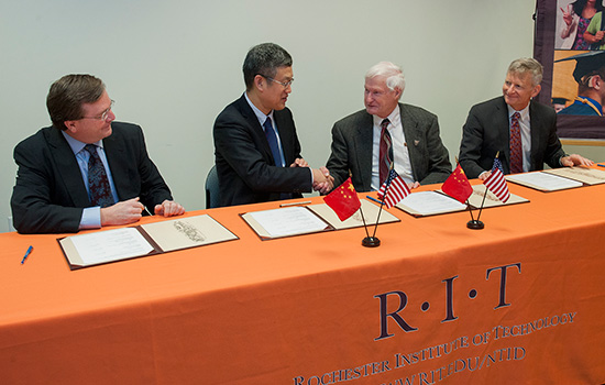 People shaking hands at table with RIT Table Sheet