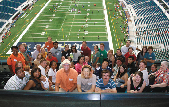 Group of people looking at the camera from the bleachers in the Cowboys stadium.