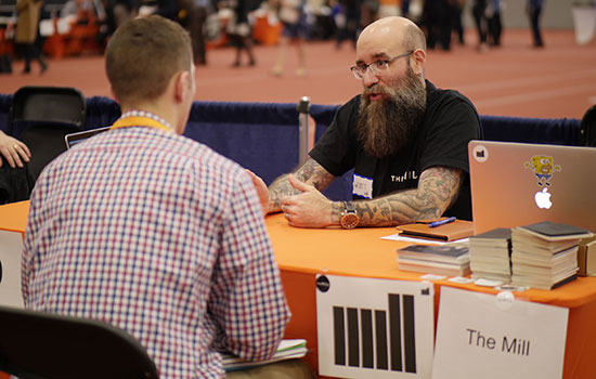 Image of two people sitting across from each other at a table in the field house.