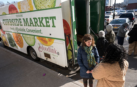 A photo of Foodlink's curbside market truck. People stand around the truck talking.