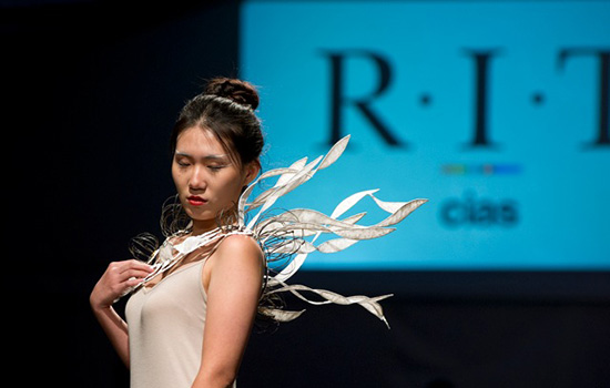 Person modeling jewelry necklace with large ribbon coming from the back on it, mimicking wings.