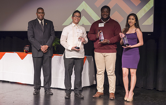 Students pose together on stage holding their student beacon awards.