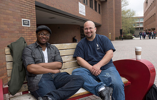 Two people posing together on bench