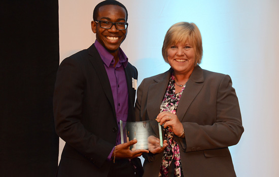 Two people posing with award on stage