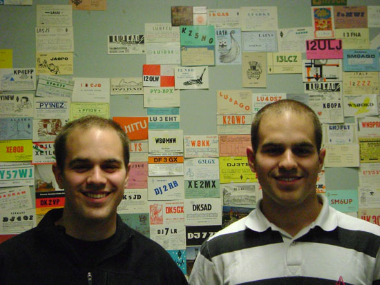 Two Students standing in front of board with amateur radio operator call signs.