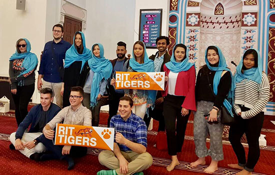 Students holding "RIT TIGERS" banners posing for a photo in Dubai.