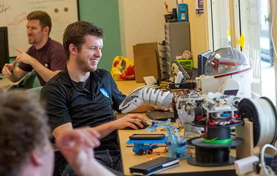 Student building robot and smiling.