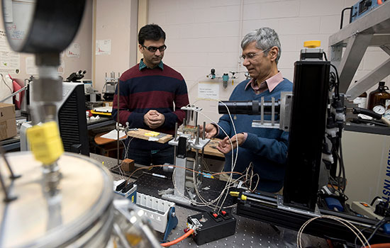 student and professor working with lab equipment.