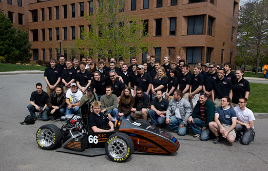 Students gathered around formula car