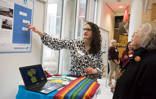 A person pointing to a poster with an audience.