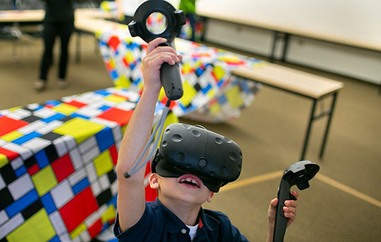 A child using a virtual reality headset and controllers at Imagine RIT.