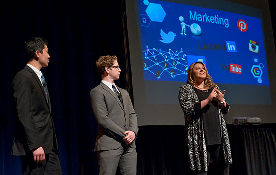 Three people standing on stage presenting innovative ideas of deaf and hard-of-hearing students.