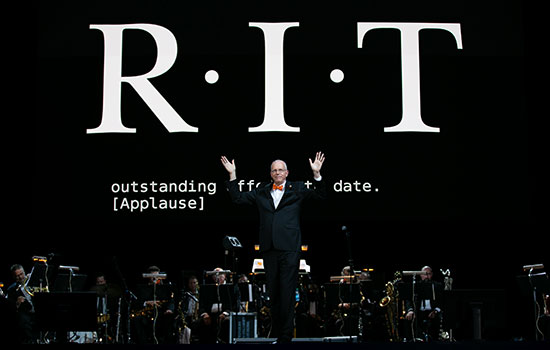 RIT President, Dr. Munson, standing on a stage in front of a band.