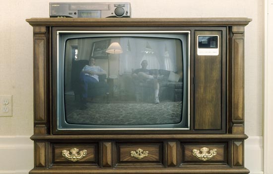 Old fashion box television with two people on screen