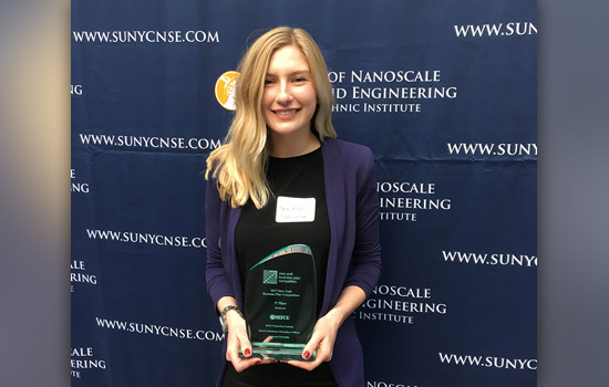 Person posing with award at conference