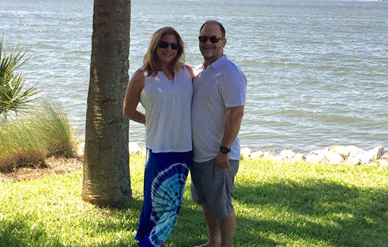 Sara and Jim Knight standing together in front of a body of water.