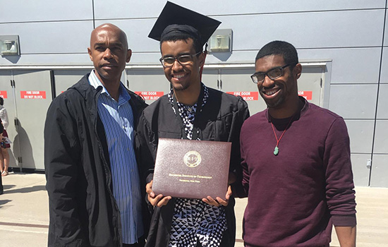 family members standing on either side of college graduate.