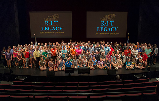 group photo of students and their family members on a stage.