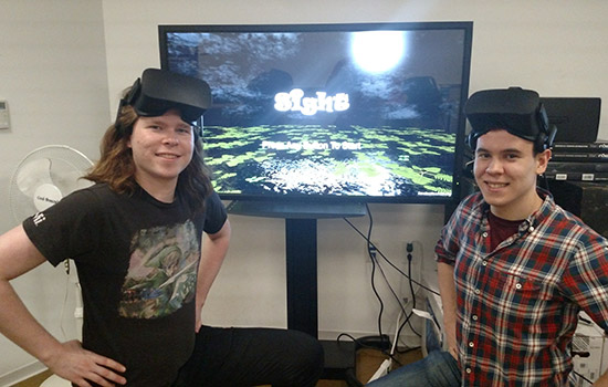 Two students wearing VR headsets next to screen
