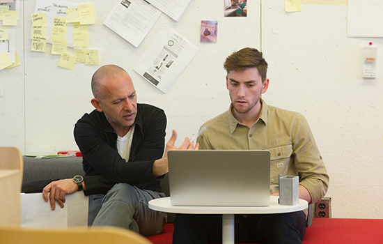 Faculty Josh Owen observes what's on a computer screen with a student.