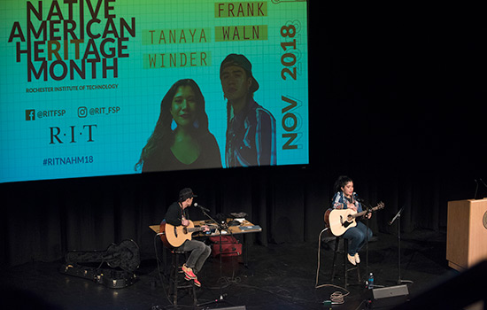 two people playing guitar on stage.