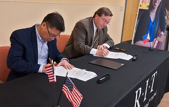 Two men at a table signing papers.