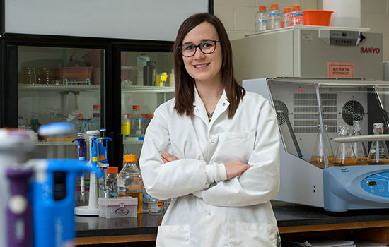 Nicole Pannullo in a white lab coat standing in a lab.
