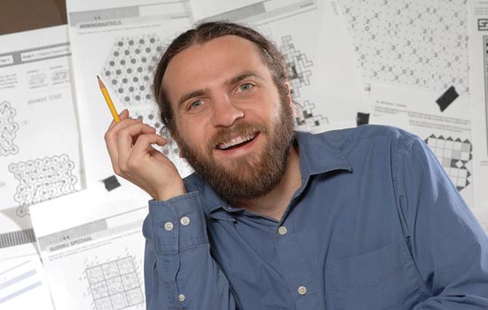 RIT Professor posing with pencil in front of puzzles