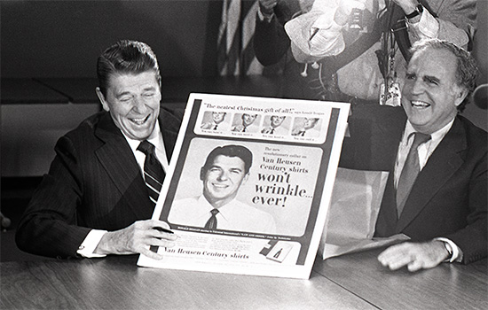 President Ronald Reagan holding poster at table