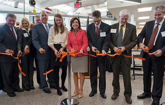 Group of people cutting orange ribbon.