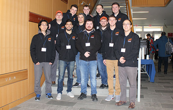 Team of RIT cybersecurity students poses for picture in front of staircase.