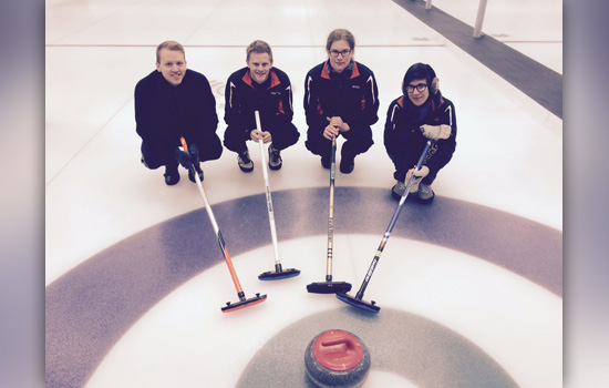 People posing near a curling puck