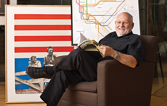 Professor posing in chair in front of maps
