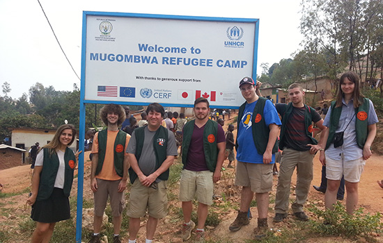 'People gathered in front of "Welcome to Mugombwa Refugee Camp"'