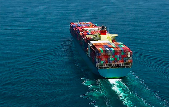 An aerial view of a large cargo ship sailing across open ocean.
