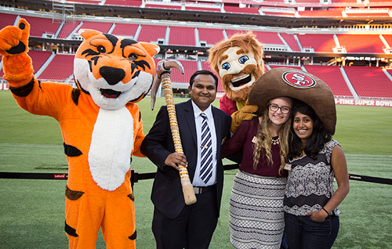 People posing in stadium with tiger mascot