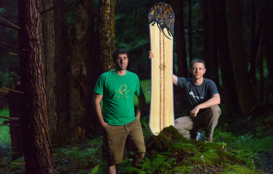 Two people posing with board in forest
