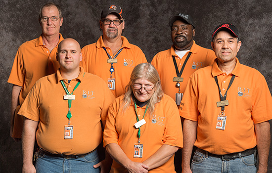 Team poses together in matching orange polos.