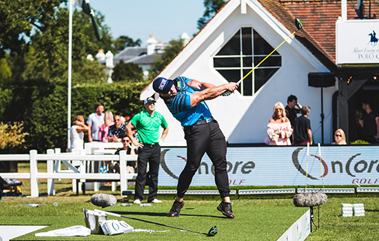 Ryan Steenberg hitting a golf ball at a competition, his arm and club still extended in the air.