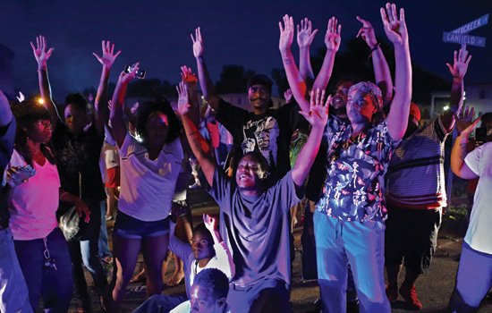 A group of people hold their arms up in the air. 