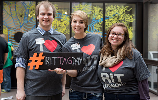Three students in matching shirts that say "I heart RIT donors" pose for a picture.