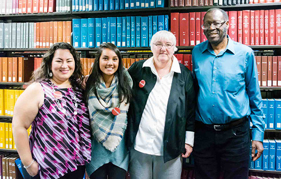 Four people together for a picture in the Wallace Library.